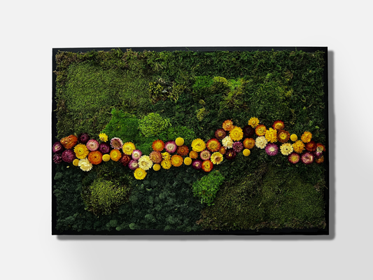 Large moss wall art of varying shades of green with a horizontal river of yellow, pink, and dark purple flowers in the middle