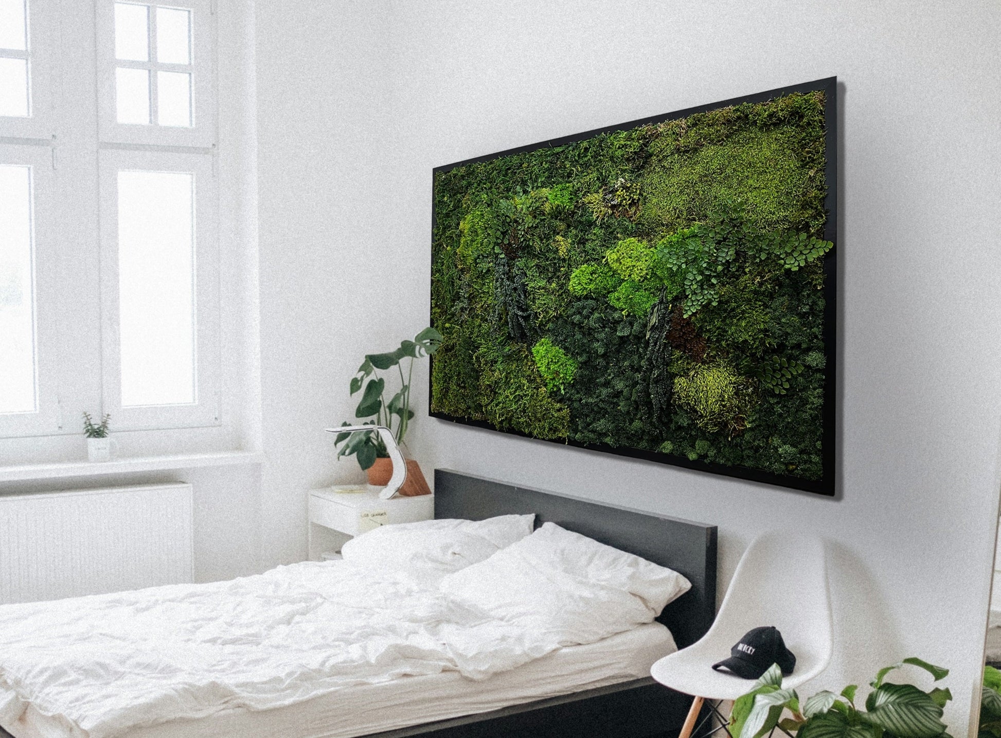 The moss wall art shown above a bed